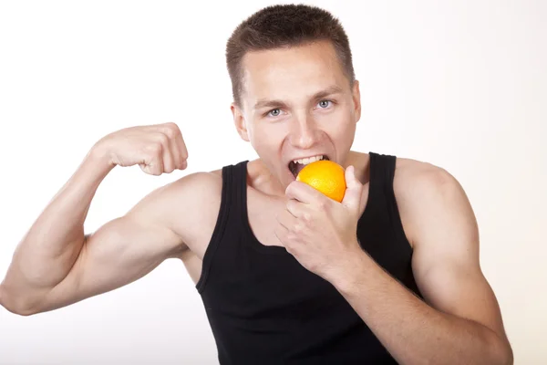 Молодий привабливий чоловік їсть апельсин — стокове фото
