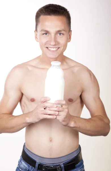 Junger attraktiver Mann hält Flasche Milch Stockbild