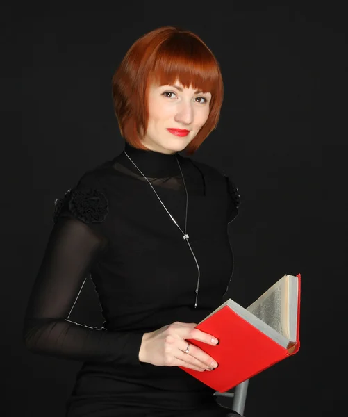 Mulher com o livro vermelho nas mãos sobre um fundo preto — Fotografia de Stock