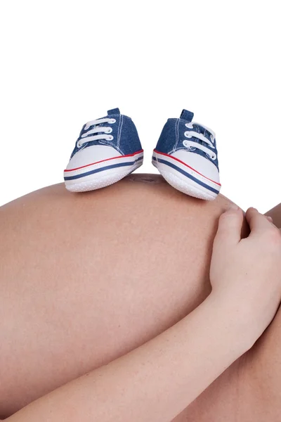 Nahaufnahme einer schwangeren Frau mit blauen Babyschuhen — Stockfoto