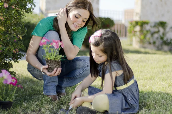 Jovem bela mãe plantando algumas flores com sua filha — Fotografia de Stock