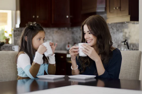 美しい若い母親は彼女の娘と一緒に、コーヒーを飲む — ストック写真
