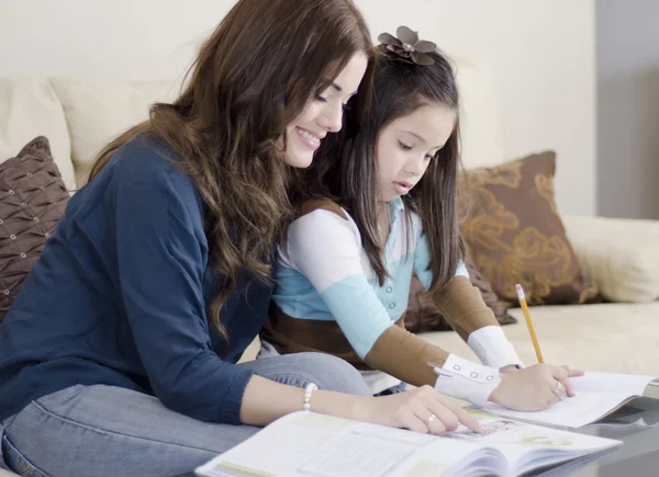 Young beautiful mother coloring a book with her daughter — Stock Photo, Image