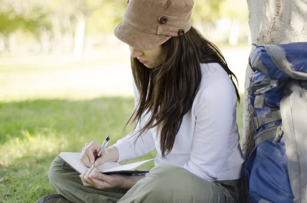 Jonge mooie vrouw schrijven in een dagboek over haar trektocht — Stockfoto