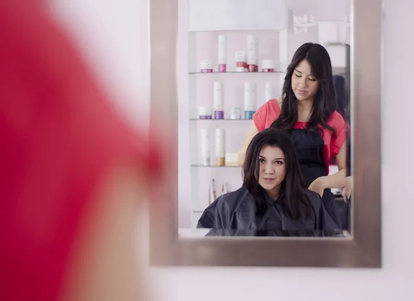Kadeřníkem a klientem při pohledu na vlasy přes zrcadlo — Stock fotografie