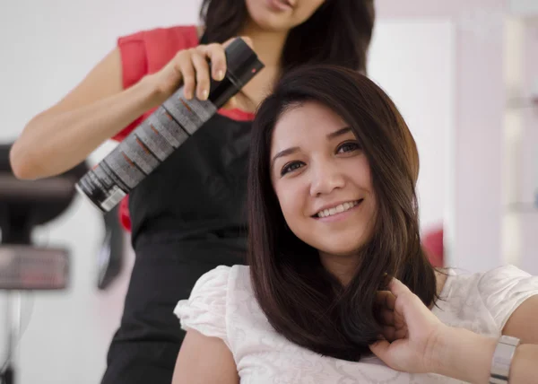 Jonge vrouwelijke Kapper spray op haar van de klant van toepassing — Stockfoto