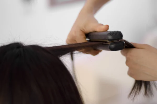 Parrucchiere femminile che raddrizza i capelli di un cliente — Foto Stock