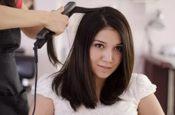 Peluquería femenina alisando el cabello de un cliente — Foto de Stock