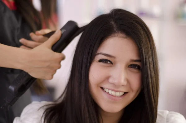 Female hairdresser straightening the hair of a client — Stock Photo, Image