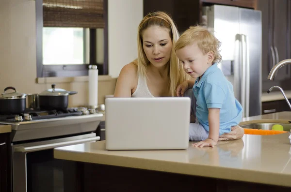 Mladá krásná matka něco dávat synovi v její laptop — Stock fotografie