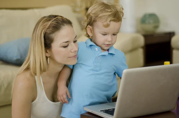 Νεαρή όμορφη μητέρα χρησιμοποιώντας ένα φορητό υπολογιστή με το γιο της — Φωτογραφία Αρχείου