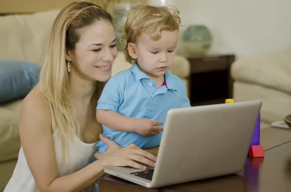 Unga vackra mamma med en bärbar dator med hennes son — Stockfoto