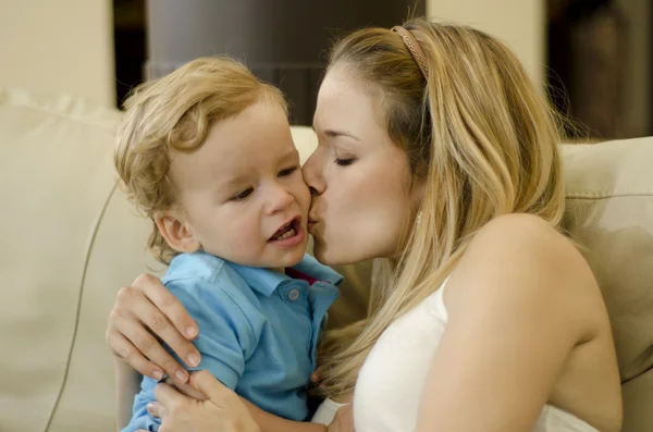 Vacker ung mamma kysser hennes son på kinden — Stockfoto