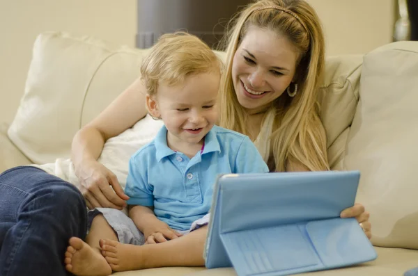 Bela jovem mãe brincando com seu filho e um tablet — Fotografia de Stock
