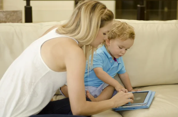 Hermosa joven madre jugando con su hijo y una tableta — Foto de Stock