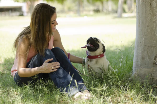 Cute girl relaxing at the park with her pug dog — Stock Photo, Image