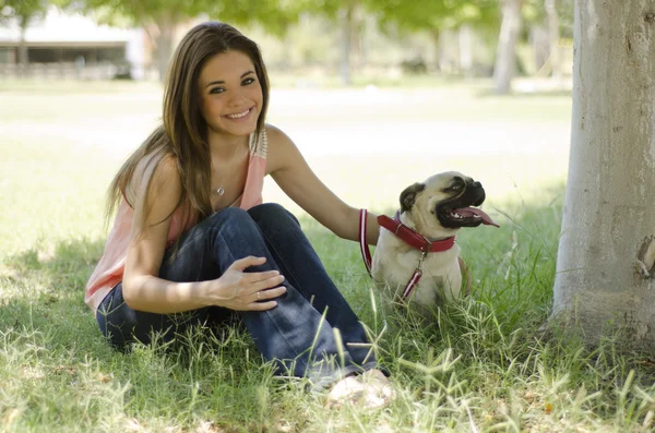 Милая девушка отдыхает в парке со своей собакой-мопсом — стоковое фото