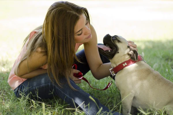 Młoda piękna kobieta z psem Mops w parku — Zdjęcie stockowe