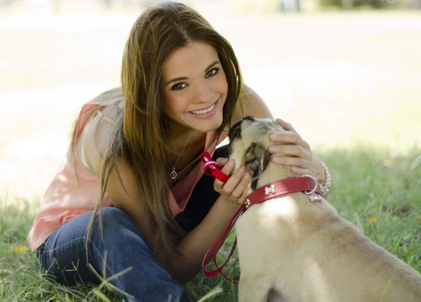 Портрет милой девушки с собакой-мопсом в парке — стоковое фото