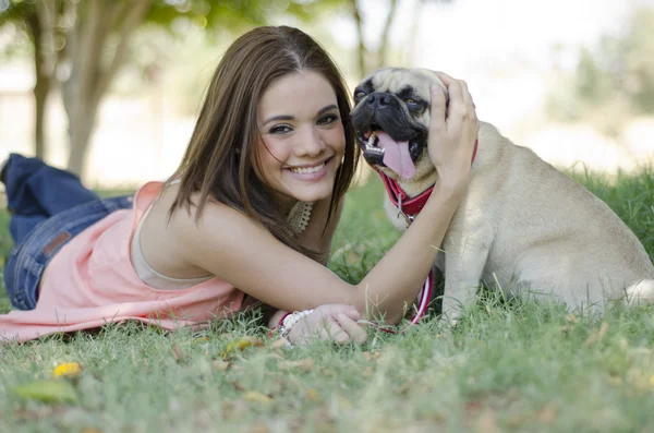 Söt ung kvinna spendera lite tid med hennes mops hunden på park — Stockfoto