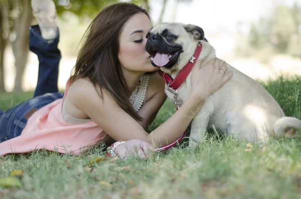 Nette junge Frau küsst ihren Hund im Park — Stockfoto
