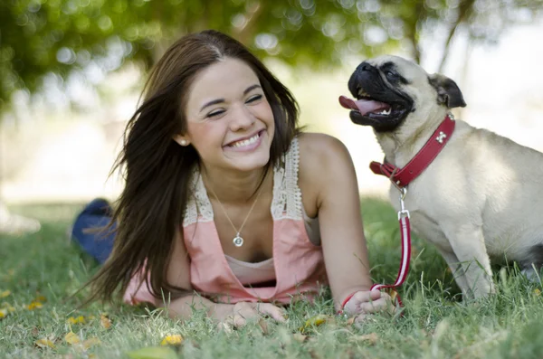 Милая молодая женщина проводит некоторое время со своей собакой-мопсом в парке — стоковое фото