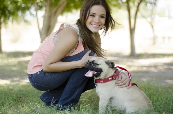 Портрет милой девушки с собакой-мопсом в парке — стоковое фото