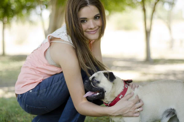 Portret van schattig meisje met haar hond pug in het park — Stockfoto