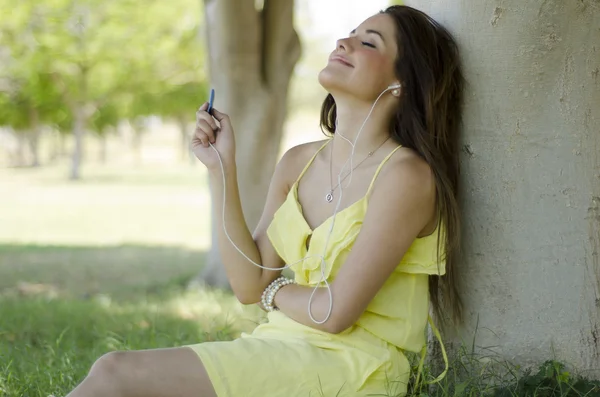 Roztomilá žena poslouchá hudbu a relaxaci v parku — Stock fotografie