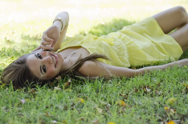Jovem mulher bonita relaxando no parque durante uma chamada — Fotografia de Stock