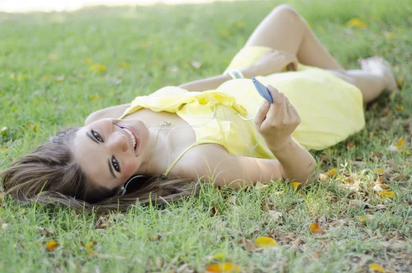 Mladá krásná žena, poslouchá hudbu a relaxaci v parku — Stock fotografie