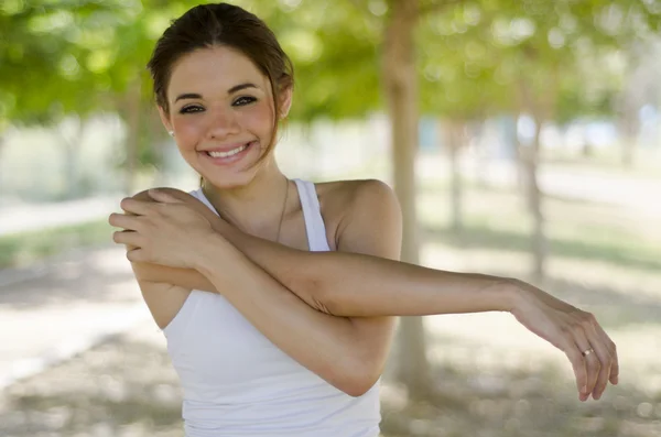 Молодая красивая женщина делает несколько упражнений на растяжку в парке — стоковое фото