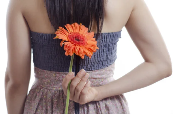 Young woman hiding a flower behind her back — Stock Photo, Image