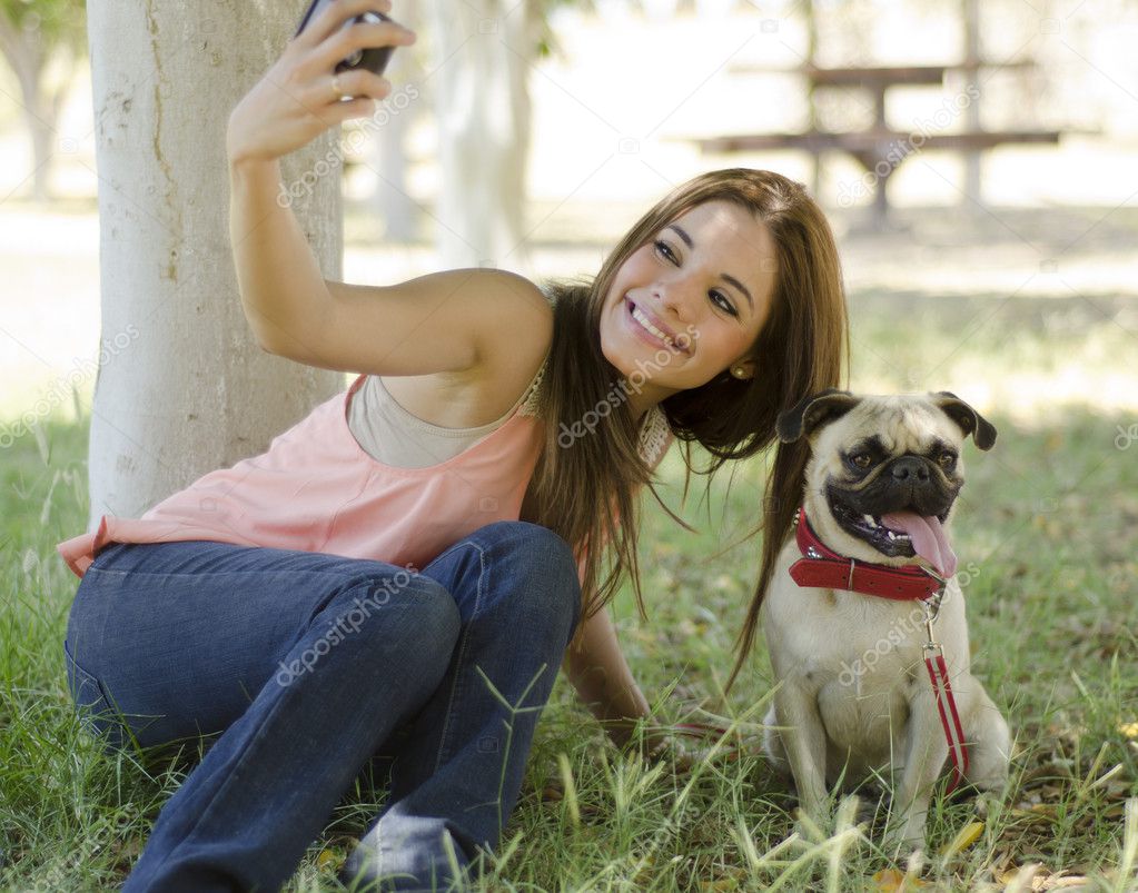 Young beautiful woman taking a picture with her dog at the park