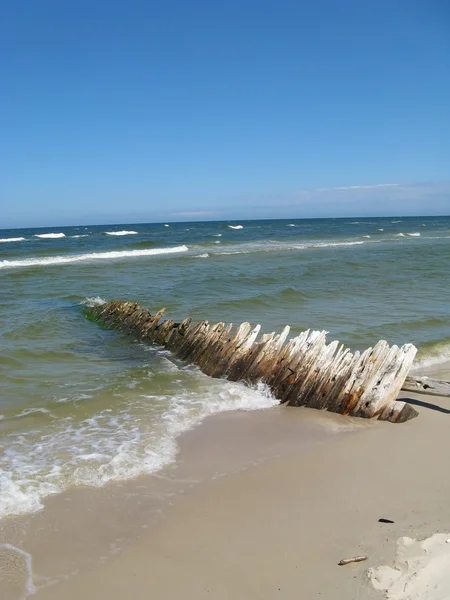 Песчаный пляж с морем и туловищем корабля — стоковое фото