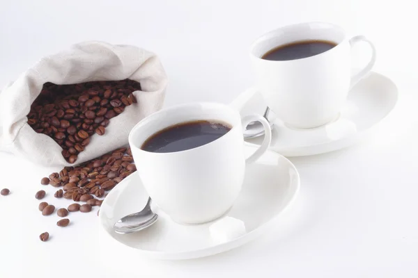 Koffie kopjes ind koffiebonen uit zak in de witte tafel — Stockfoto