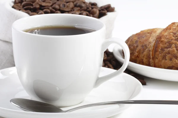 Framifrån av en kopp hett kaffe med croissanter och bönor — Stockfoto