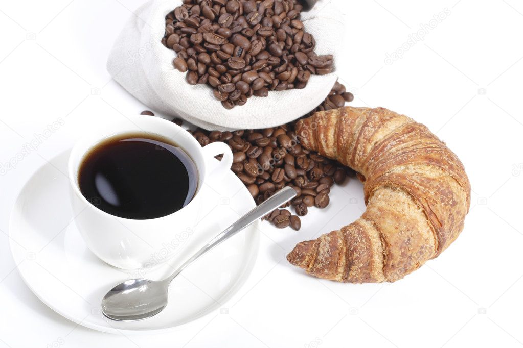 Cup of hot coffee with croissants and beans