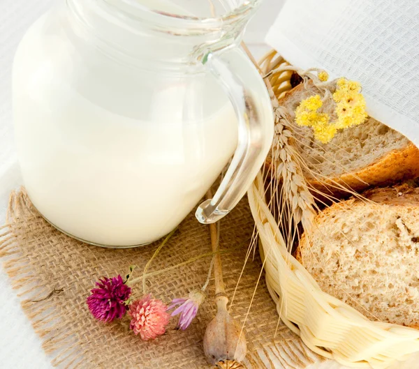 Jug with milk, bread and wild flower — Stock Photo, Image