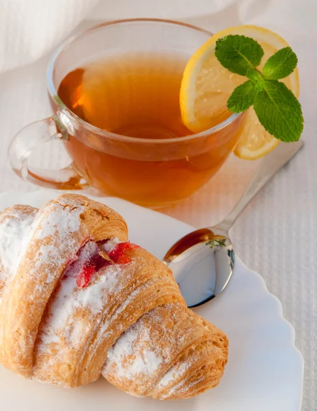Croissant com geléia e chá com um limão — Fotografia de Stock
