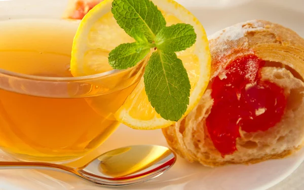 Круассан с джемом и чай с лимоном — стоковое фото