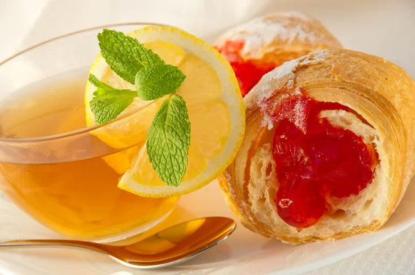 Croissant com geléia e chá com um limão — Fotografia de Stock