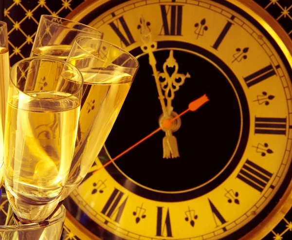 Різдвяна листівка. Окуляри шампанського напередодні Нового року проти старовинного настінного годинника — стокове фото