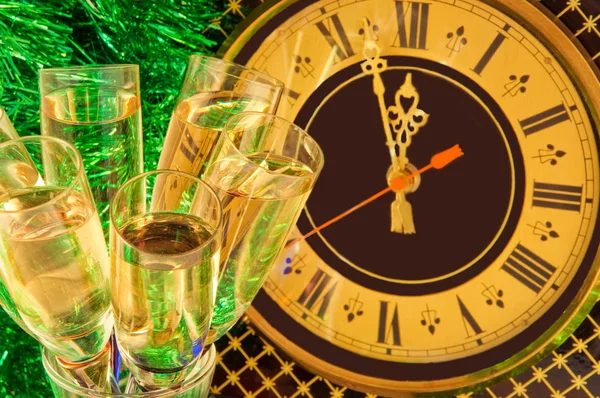 Tarjeta de Navidad. Las copas del champán en la víspera de Año Nuevo contra el reloj antiguo de pared — Foto de Stock