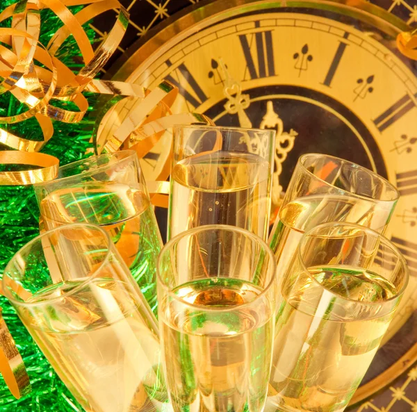 Weihnachtskarte. Champagnergläser an Silvester gegen eine antike Wanduhr — Stockfoto