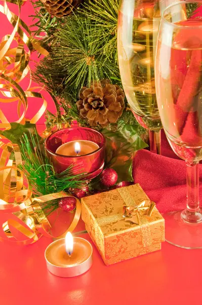 Christmas card. Champagne, a branch of a fur-tree and a candle on a red background — Stock Photo, Image