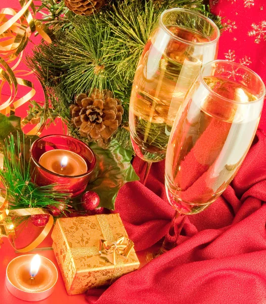 Kartki świąteczne. szampan, oddział choinkowe i świeca na czerwonym tle — Zdjęcie stockowe