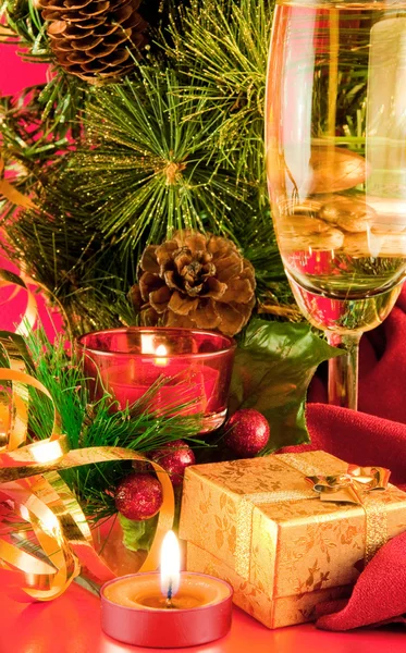 Biglietto di Natale. Champagne, un ramo di un albero di pelo e una candela su uno sfondo rosso — Foto Stock