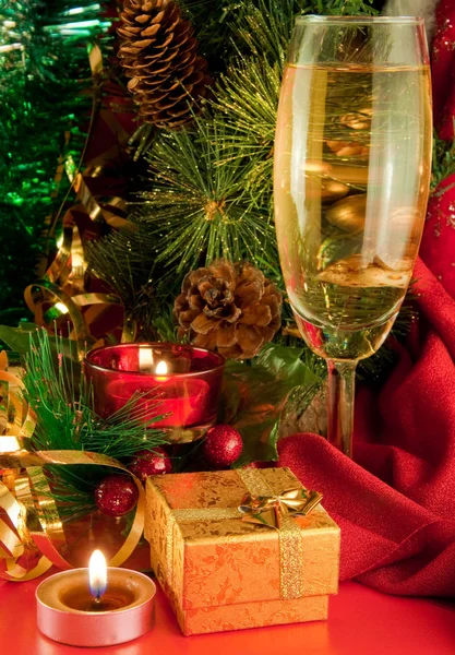 Carte de Noël. Champagne, branche d'un sapin et bougie sur fond rouge — Photo