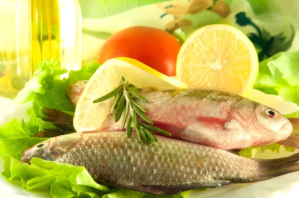 Fresh fish, crucian with a lemon and an onions, salad with olive oil — Stock Photo, Image